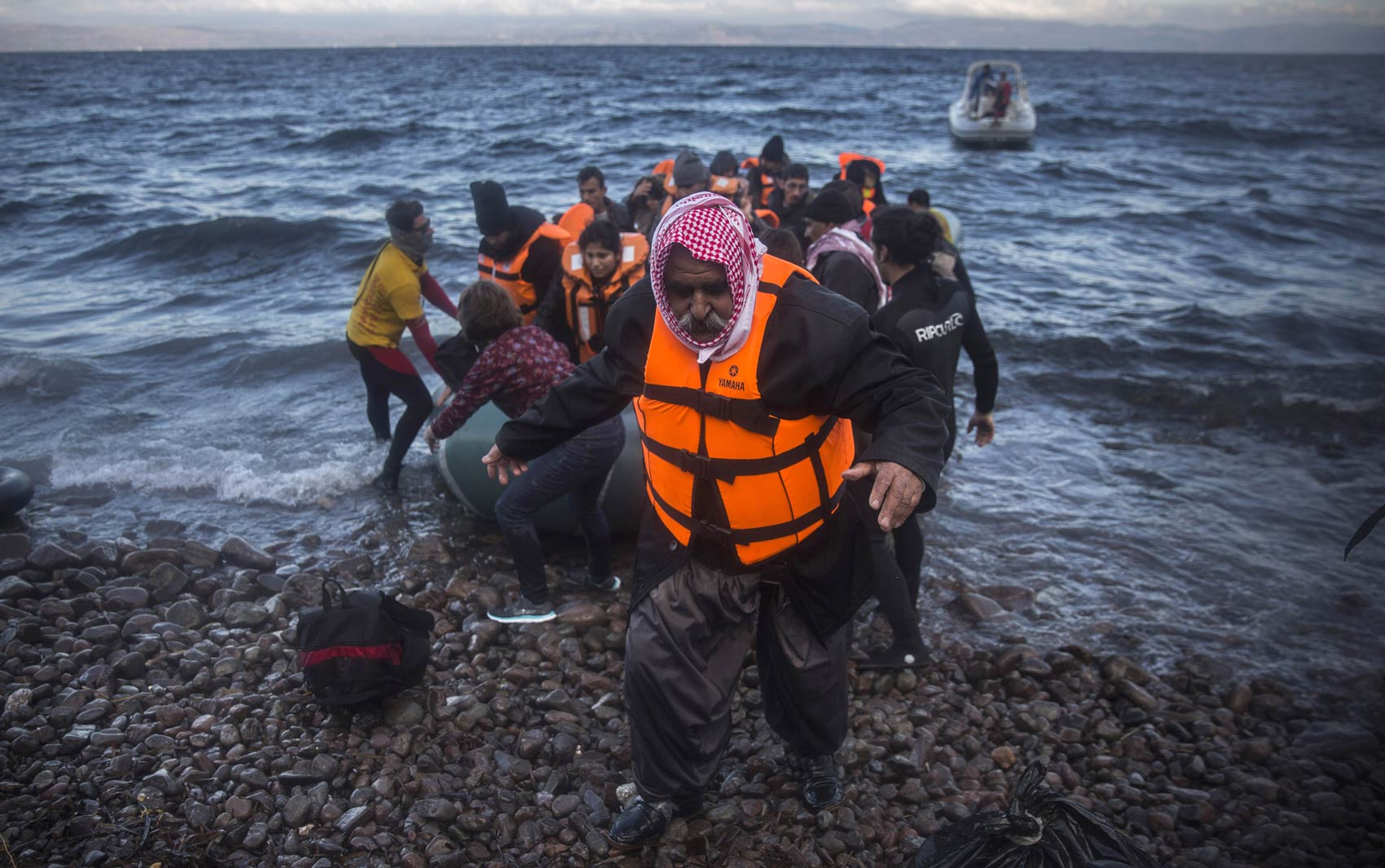 Iraquiano desembarca de um bote após cruzar o mar da costa da Turquia até uma praia de Lesbos, ilha da Grécia, com outros refugiados e migrantes. Milhares de pessoas seguem chegando à Europa, em fuga dos conflitos no oriente Médio (Foto: Santo Palacios/AP)