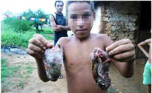 Criança exibe rato após a caça (Foto: Portal AG 1 Notícias)
