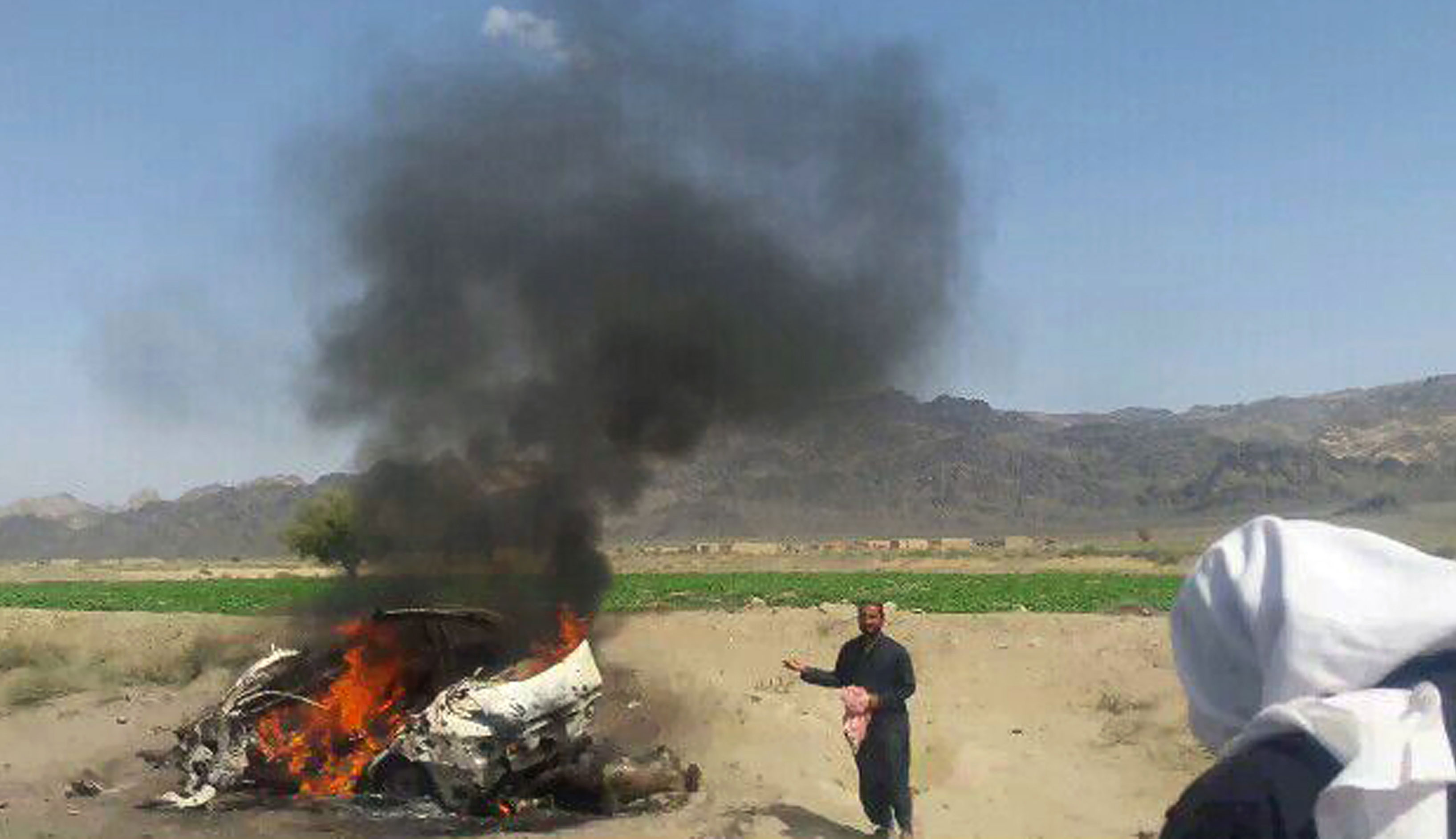 Fotografia feita no sábado mostra moradores paquistaneses em volta de um veículo destruído por um drone, no qual o líder Akhtar Mansour estaria. (Foto: AFP)