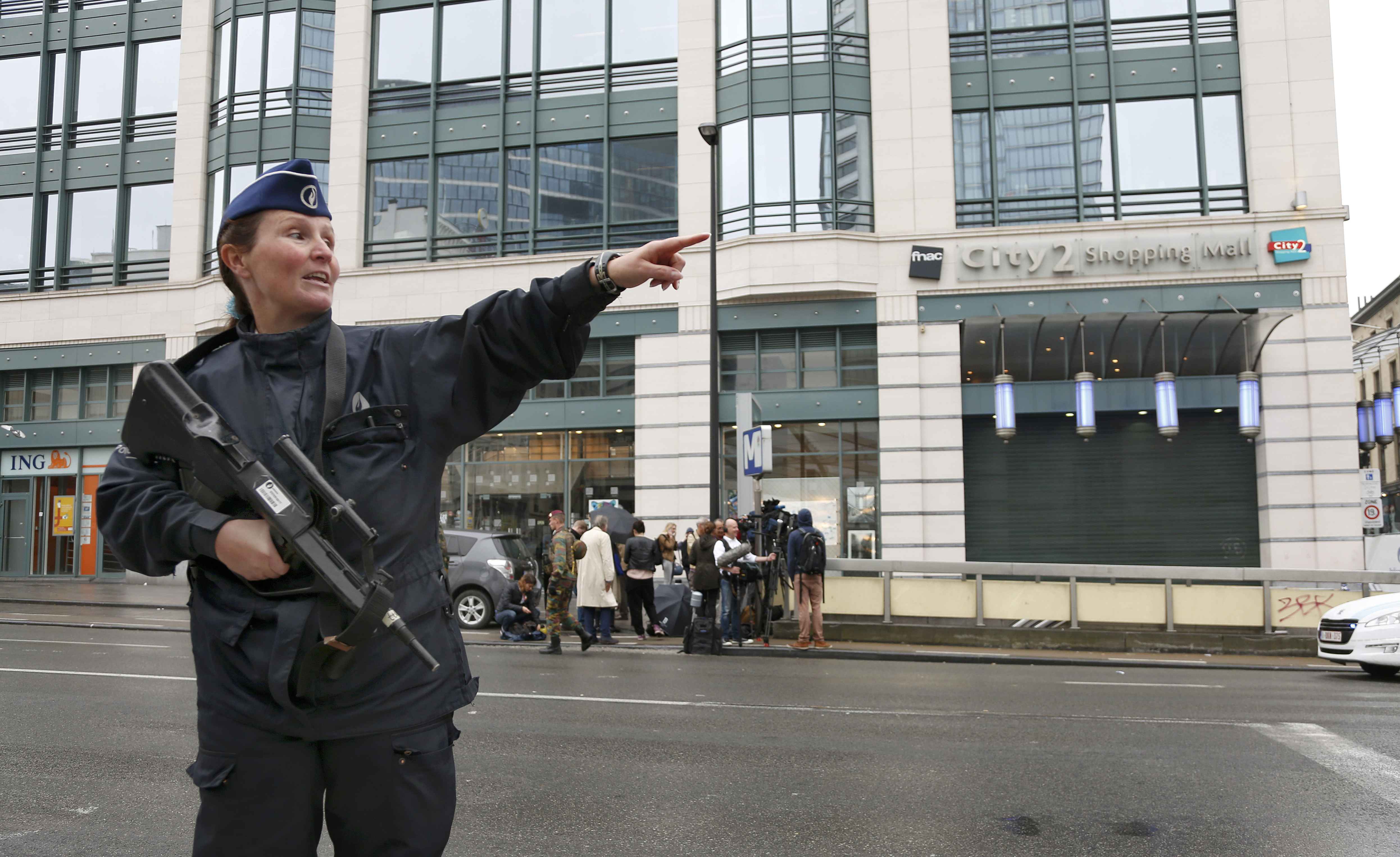 Policial dá orientações em frente a shopping City2, em Bruxelas (Bélgica), evacuado após ameaça de bomba (Foto: Francois Lenoir/Reuters)