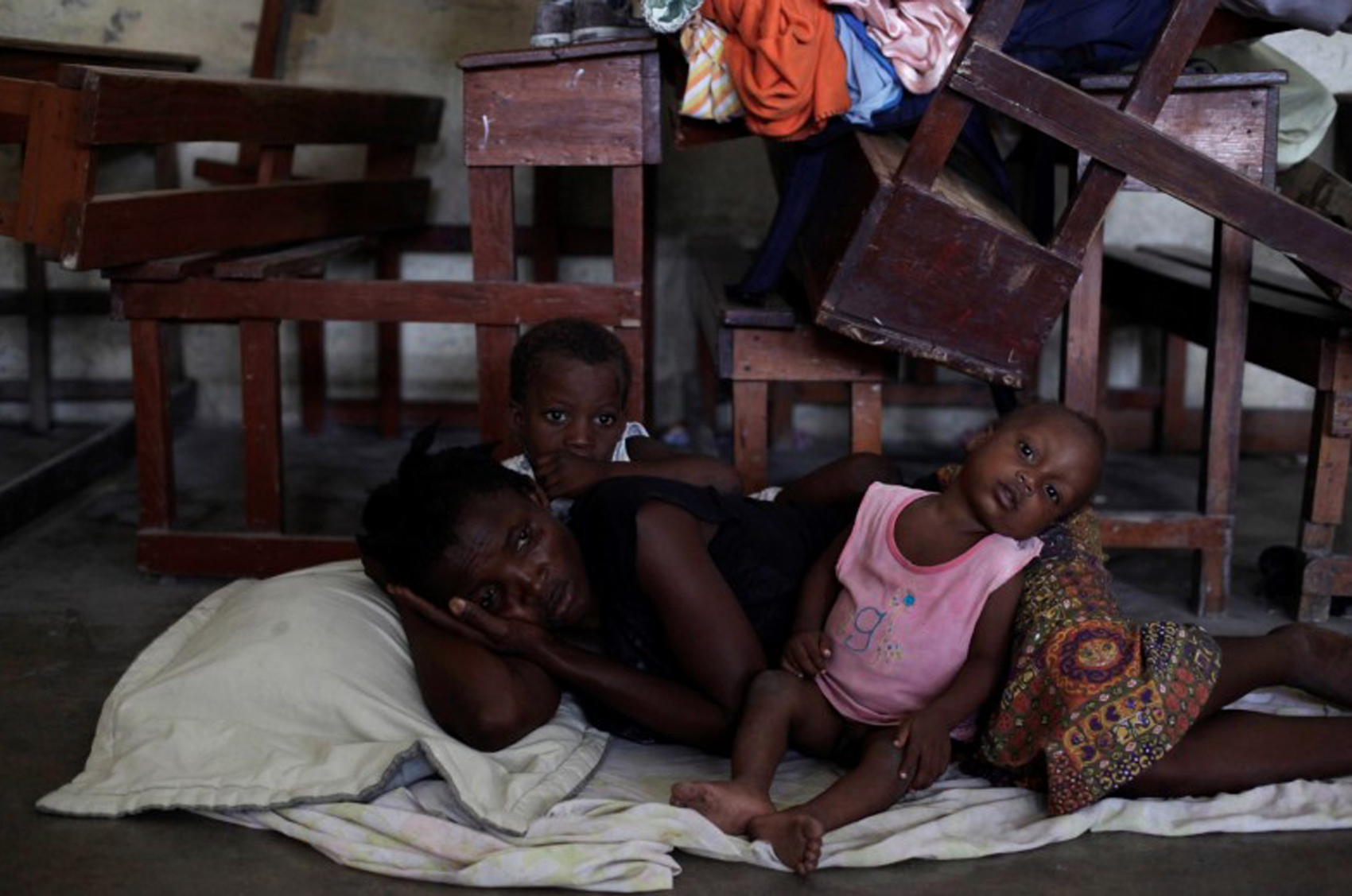 Mulher com duas crianças descansa deitada no chão de abrigo montado em escola em Les Cayes, no Haiti (Foto: Andres Martinez Casares/ Reuters)